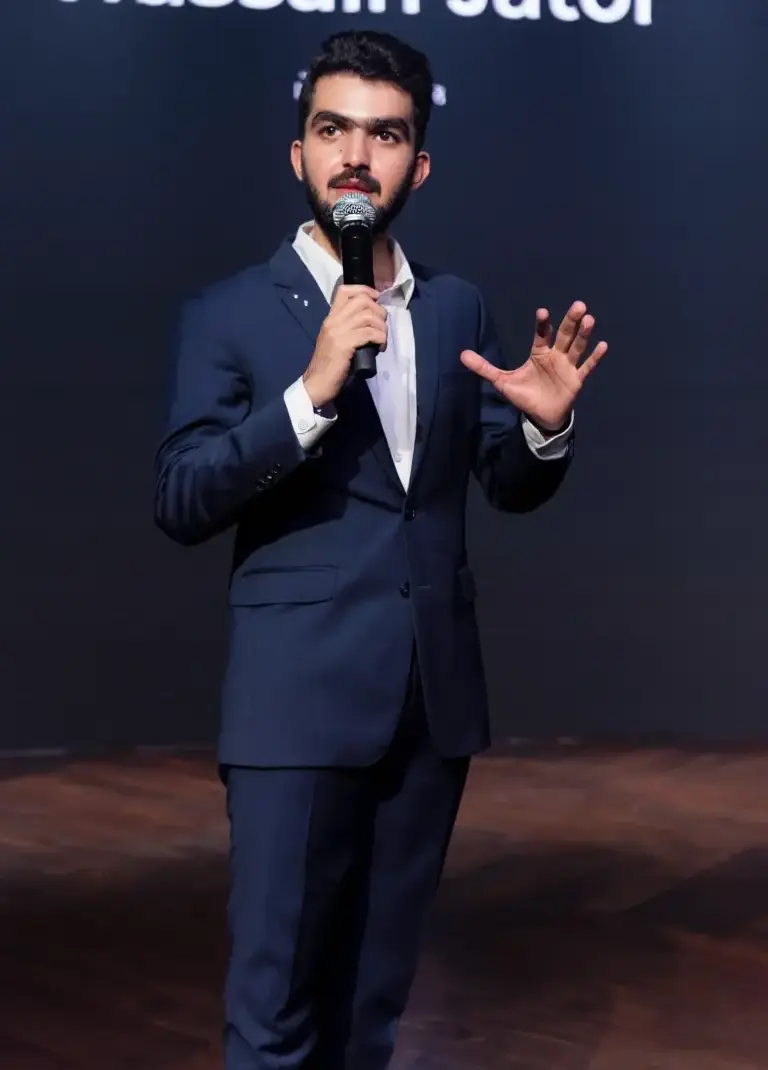 Hussain Jatoi speaking on stage with microphone